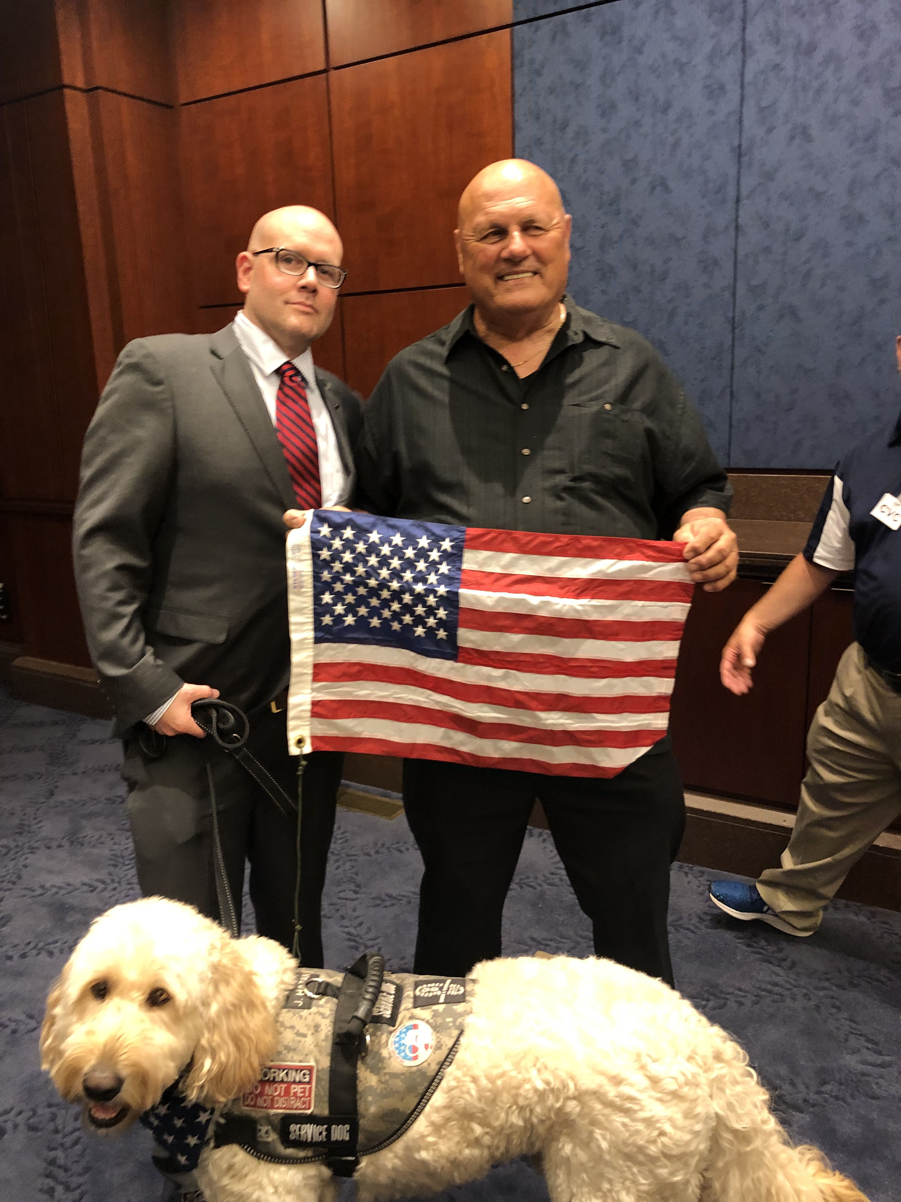 Jaime Hazan with Joe Zadroga and service dog Bernie holding an American flag